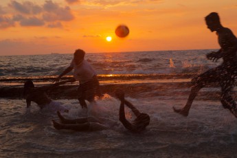 Locals enthusiastically playing water soccer at sunset.