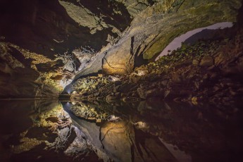 
Hang En Cave: In the lake in front of the huge boulder pile three lights reflect. In the lights you can see black outlines of our three lightning technicians.