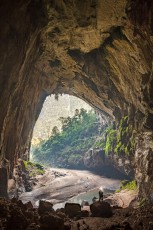Der riesige Ausgang der Hang En Cave. Etwas oberhalb links vom Mann auf dem Felsen im Vordergrund erkennt man den winzig erscheinenden Höhlenforscher Ian 'Watto' Watson im ausgetrockneten Flussbett.

