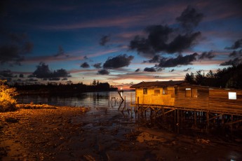 Miri: Harbour street lights mingle with the last daylight, and illuminate a fisherman's stilt house.