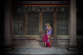 Amelie und studieren die eingemeißelten Zeichen an der Innenmauer eines chinesischen Tempels bei Georgetown, Malaysia.