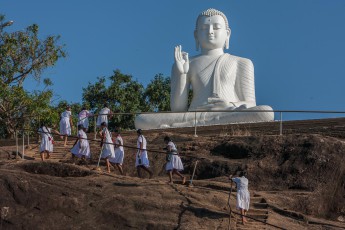 Mihintale: Schoolgirls climbing a Buddha statue. 