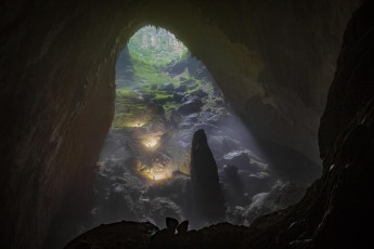 Drei von uns klettern mit eingeschalteten Stirnlampen etwa 80 Meter hoch zur zweiten Doline. Auf dem Grund der zweiten Doline hat sich im Laufe der Jahrtausende ein eigenes Ökosystem mit Höhlendschungel gebildet. Von hier aus sind sogar die Bäume zu erkennen.
