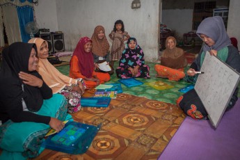 It's pitch black as the first women enter the room. They directly come from their Friday prayers in the mosque. Now WWF teacher Antika teaches reading and writing. For many women, this is the first school they visit in their lifetime. Each woman in the circle reads the ABC off the whiteboard. Their papers get filled with self-written letters, kids help their mothers and grandmothers. And there is a lot of laughter. At the end of the lesson, a hunter-tiger story is read, in which the tiger turns out to be a hero. This is how you erase images of arc enemies.