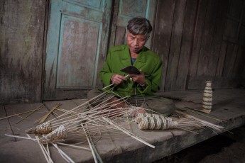 Dinh Lau, geb. 1955, gehört zur ethnischen Minderheit der Aram, die in Vietnam nur noch knapp 200 Mitglieder umfasst. Hier baut er gerade flaschenähnliche Aal-Reusen aus Bambus. Nach Gründung des Nationalparks siedelte man sein gesamtes Dorf an den Rand des Parks. Eine fragwürdiges Projekt, da es den Aram untersagt ist, für ihren Lebensunterhalt in ihrem ursprünglichen Lebensraum im Park zu jagen oder sammeln. Heute sind sie in hohem Maße von staatlichen Subventionen abhängig.
