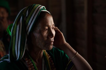 Burma/Myanmar: A Chin woman of an animist village in a remote spot in the vicinity of Mindat. The photo was taken during a special ceremony, in which nine oxen were sacrificed, and their heads hung on poles.
