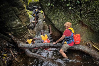 Santu Island: After crossing the Millennium Cave, an adventurous climb through niches, over tree trunks, in the water and along large rock monsters follows.