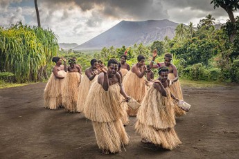 Women from the village of Imaio during a Kastom dance performance, with the smoking Yazur volcano in the background.