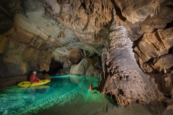 Cave guide Gašper Modic navigates his boat through the crystal-clear waters of Križna Cave, navigating between stalactites and stalagmites that are thousands of years old. The constant water temperature of 8 degrees Celsius makes this underground world a unique ecosystem.