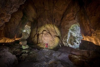 In the monumental Mahorčič cave, part of the Škocjan cave system, guide Borut Lozej becomes a miniature figure in front of titanic limestone walls. Daylight streams through the natural portals, transforming the UNESCO World Heritage Site into a cathedral of light and shadow.