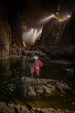 Like a mountaineer in the Alps of the underworld, guide Borut Lozej stands on a rock in the underground Reka River. Further up, lights illuminate the visitor paths through Europe's largest underground gorge.