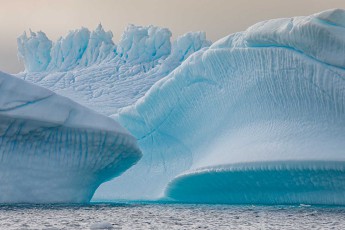 Eisberge verschmelzen zu einer Symphonie aus Blau und Weiß. Schmelzwasserrillen haben filigrane Muster in die Flanken gezeichnet.